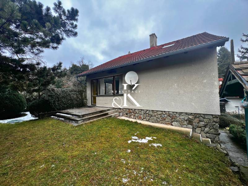 Chata u Modré s travnatým pozemkem, kamennými schody a jehličnatými stromy.