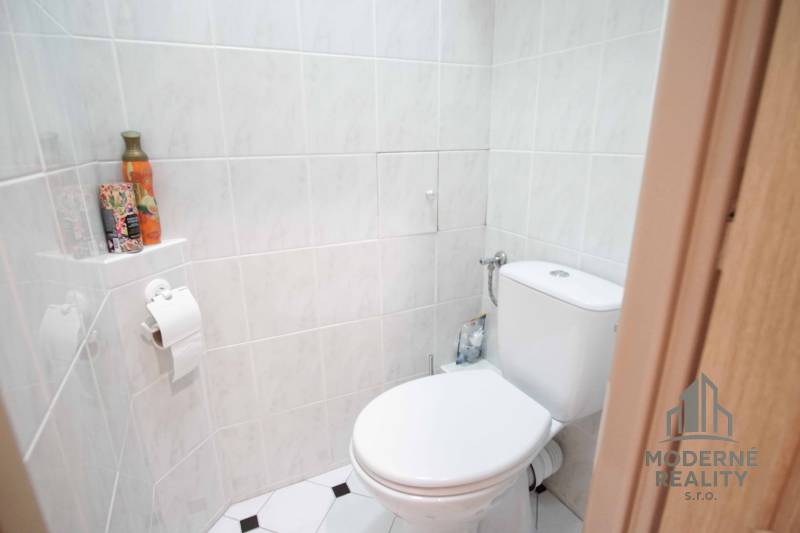 Toaleta s keramickými obklady, držák na toaletní papír, dekorativní doplňky, 4pokojový byt.