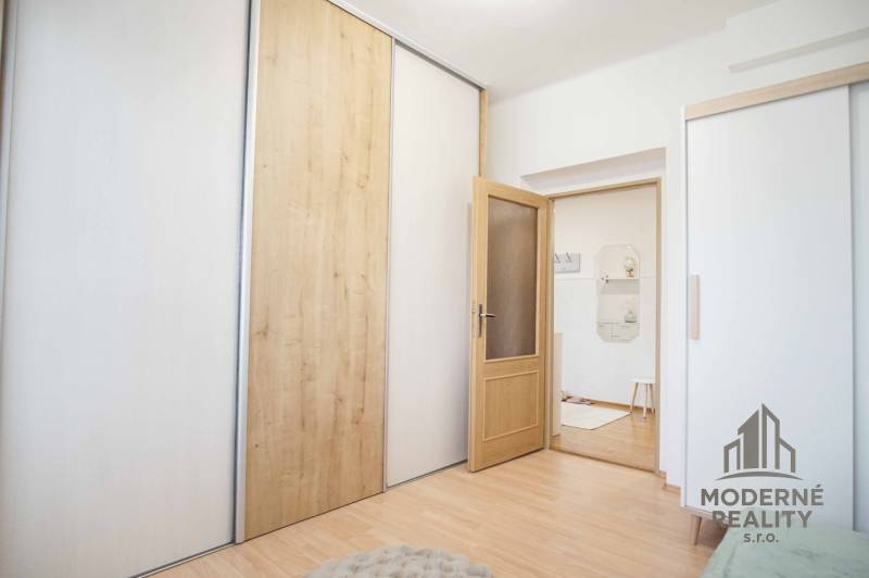 Interiér 4pokojového bytu s podlahou s dřevěným dekorem a posuvnými skříněmi.