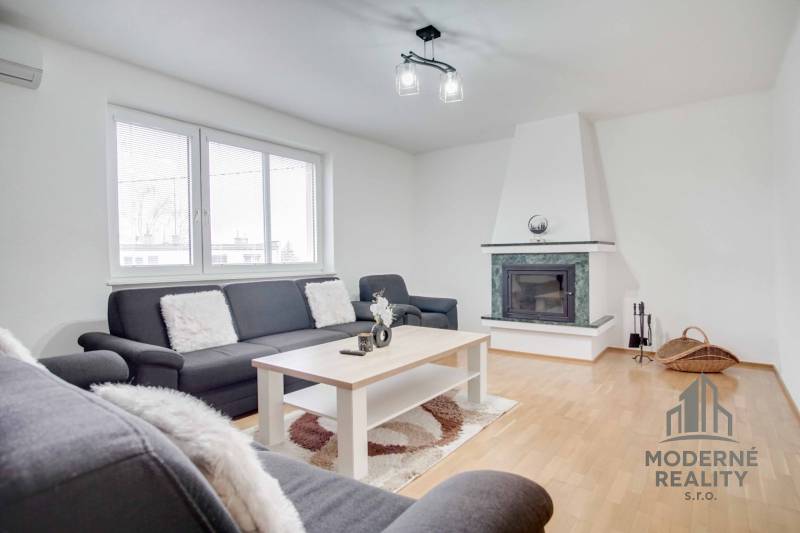 Obývací pokoj ve 4pokojovém bytě s krbem a podlahou s dřevěným dekorem.