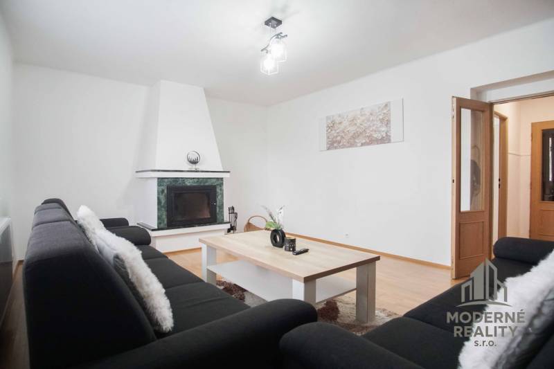 Obývací pokoj ve 4pokojovém bytě s krbem a podlahou s dřevěným dekorem.