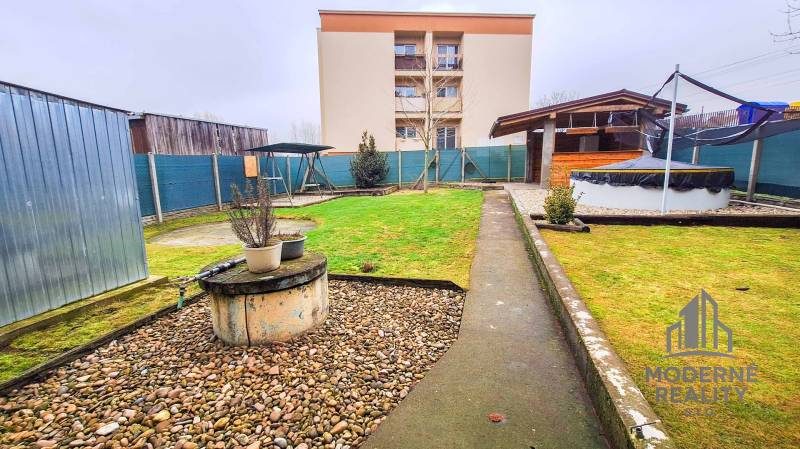 Zahrada u 4pokojového bytu v Kolte se zelení, kůlnou a venkovním krytým posezením.