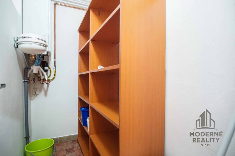 Úložný prostor s policemi a umyvadlem ve 4-pokojovém bytě.