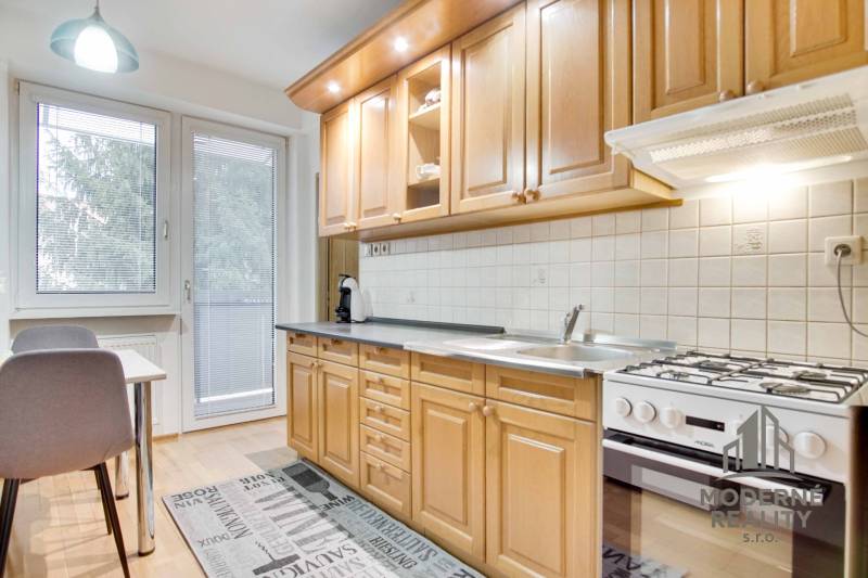 Kuchyně ve 4-pokojovém bytě s podlahou s dřevěným dekorem a jídelním koutem.