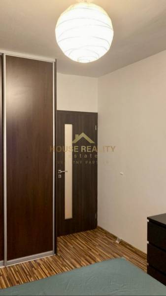 Interiér s tmavou vestavěnou skříní, dveřmi a podlahou s dřevěným dekorem v 3-pokojovém bytě.