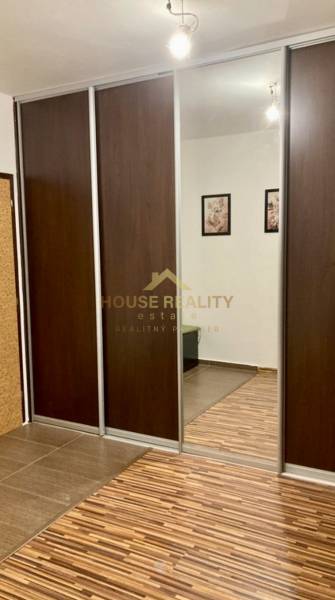 Skříň s posuvnými dveřmi a zrcadlem v 3-pokojovém bytě s podlahou s dřevěným dekorem.