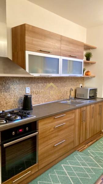 Kuchyně s dřevěným dekorem a vestavěnými spotřebiči ve 3pokojovém bytě.