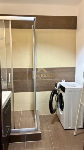 Koupelna se sprchovým koutem a pračkou v 3-pokojovém bytě.