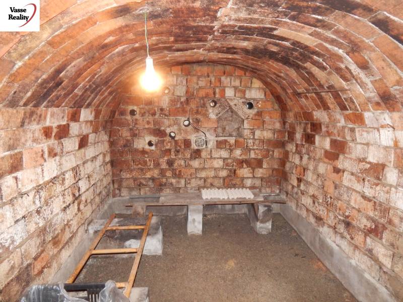 Sklep s cihlovými stěnami a klenutým stropem v rodinném domě.