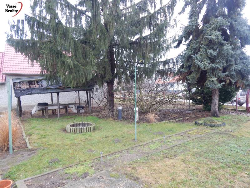 Zahrada u rodinného domu v Kravanoch nad Dunajem s altánkem a jehličnatými stromy.