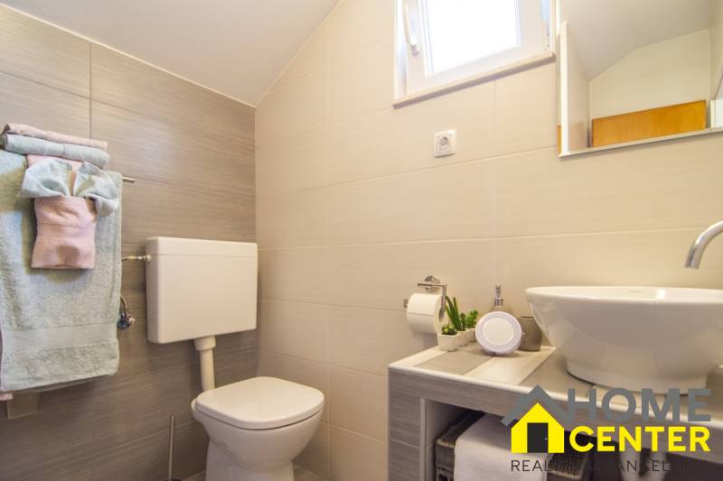 Koupelna v rekreačním apartmánu se sprchou, umyvadlem, toaletou a drobnými dekoracemi.