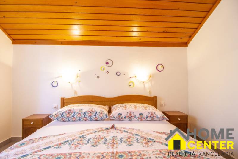 Ložnice v rekreačním apartmánu s postelí a dekoracemi na bílé stěně.