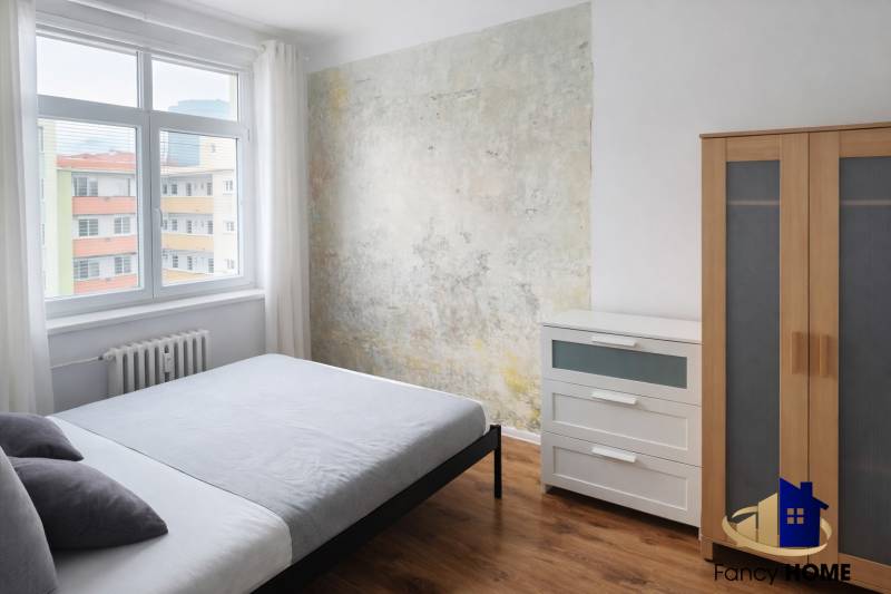 Ložnice v 2pokojovém bytě s dřevěným dekorem a originální stěnou.