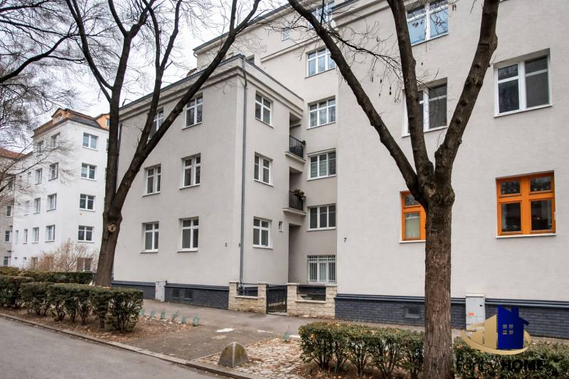 Bytový dům v Bratislavě na Jurajově dvoře, U staré prachárny. Čtyřpatrová budova, stromy, chodník.