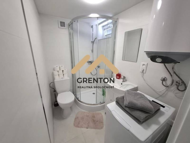 Koupelna s vanou, pračkou, bojlerem a umyvadlem v chatě. Minimalistický design.