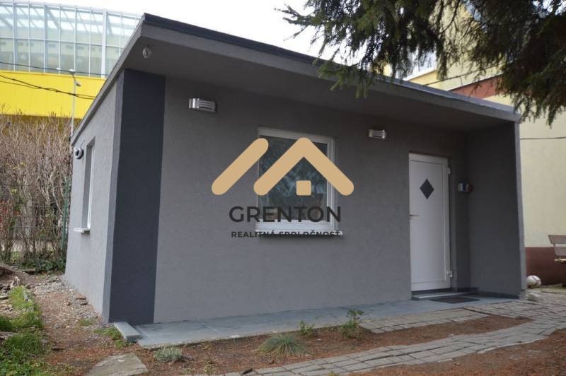 Chata s šedou fasádou v Bratislavě - Ružinově na Studené ulici, obklopená zelení.