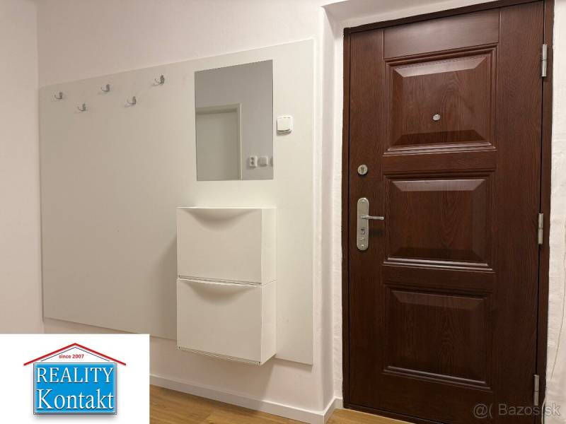 Vstupní hala ve 2-pokojovém bytě s tmavými dveřmi a podlahou s dřevěným dekorem.