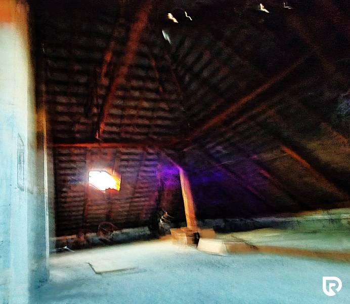 Podkroví v rodinném domě s dřevěným trámováním a oknem.