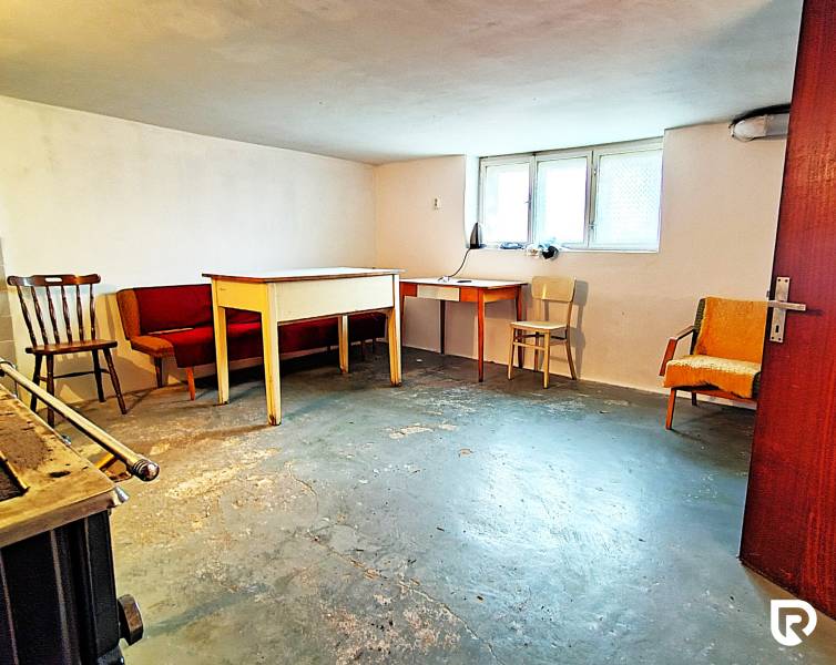 Sklep v rodinném domě s nábytkem a oknem, betonová podlaha.