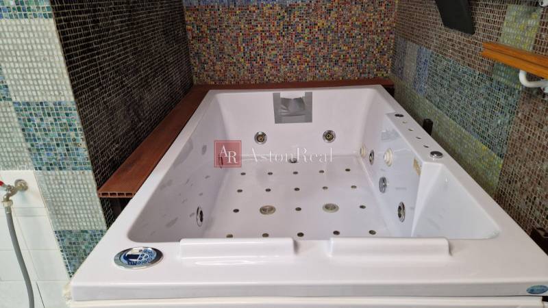 V koupelně rodinného domu je velká hydromasážní vana zdobená barevným mozaikovým obkladem.