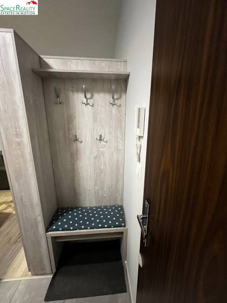 Vstupní chodba s věšáky a lavičkou v 2-pokojovém bytě.