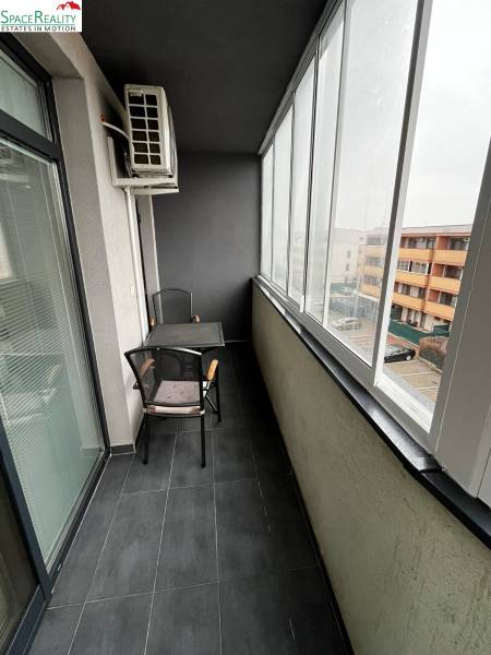 Zasklená lodžie 2-pokojového bytu na Holubej ulici v Senci s dlažbou a sezením.