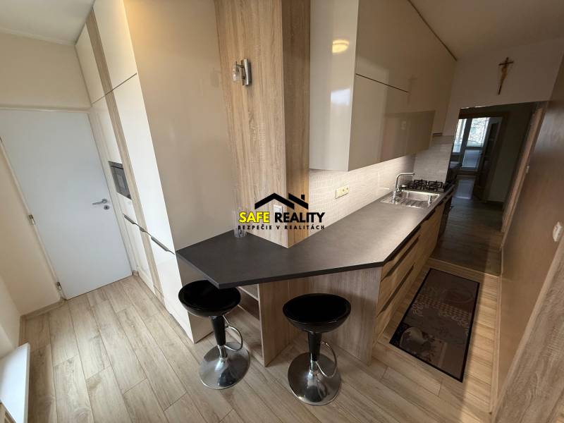 Kuchyně ve 3pokojovém bytě s podlahou s dřevěným dekorem a jídelním pultem.