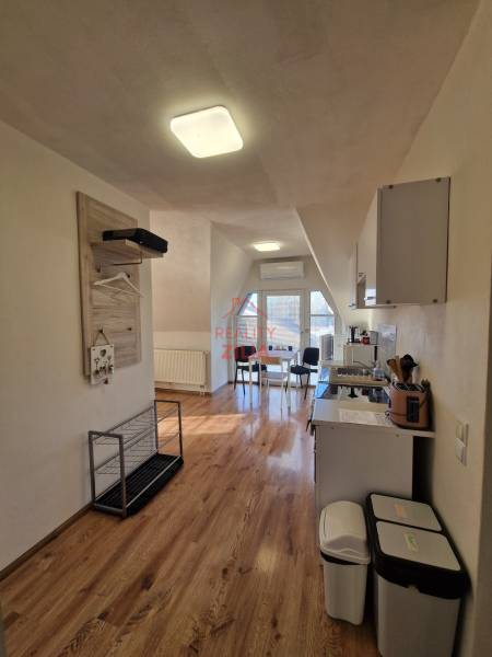 Interiér rodinného domu s kuchyní a jídelním koutem, podlaha s dřevěným dekorem.