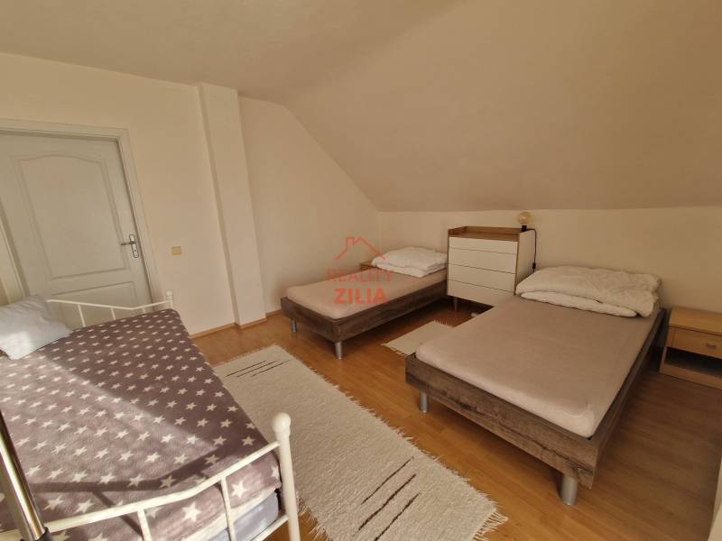 Ložnice v rodinném domě se třemi postelemi a podlahou s dřevěným dekorem.