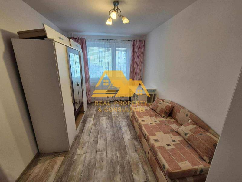 Pokoj v 3-pokojovém bytě s pohovkou, skříní a podlahou s dřevěným dekorem.