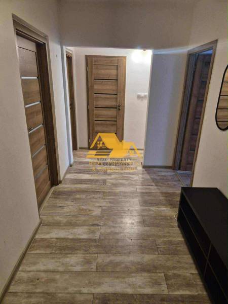 Chodba ve 3-pokojovém bytě s podlahou s dřevěným dekorem a několika dveřmi.