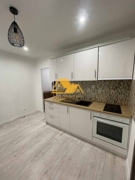 Kuchyně v 1-pokojovém bytě se světlou linkou a podlahou s dřevěným dekorem.