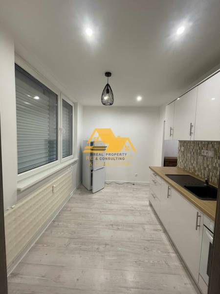 Kuchyně v 1-pokojovém bytě s podlahou s dřevěným dekorem a moderním osvětlením.