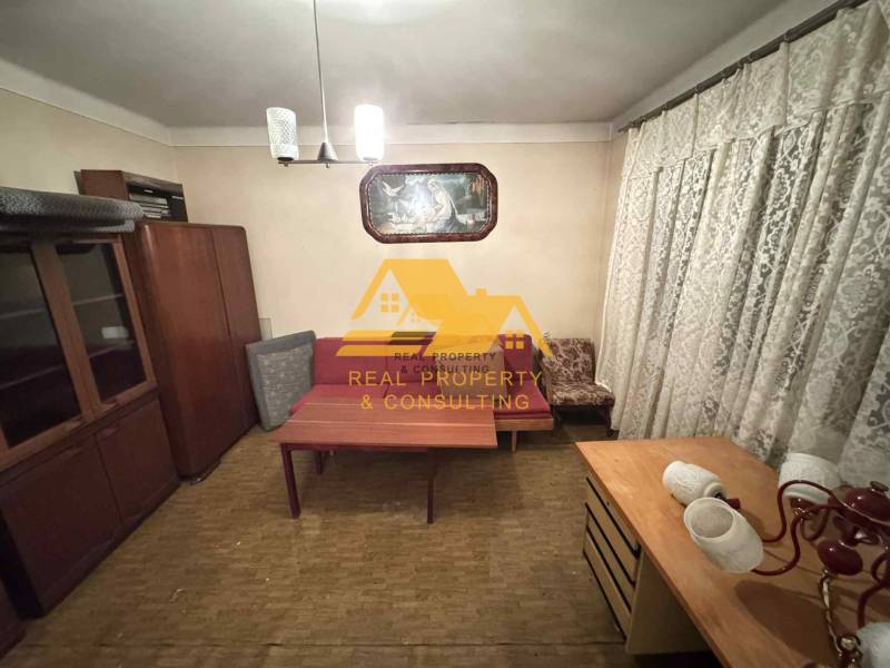 Pokoj v rodinném domě s nábytkem, závěsy a podlahou s dřevěným dekorem.