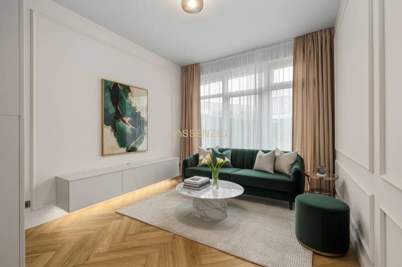 Obývací pokoj se zelenou pohovkou, dekorativním stolkem a podlahou s dřevěným dekorem.