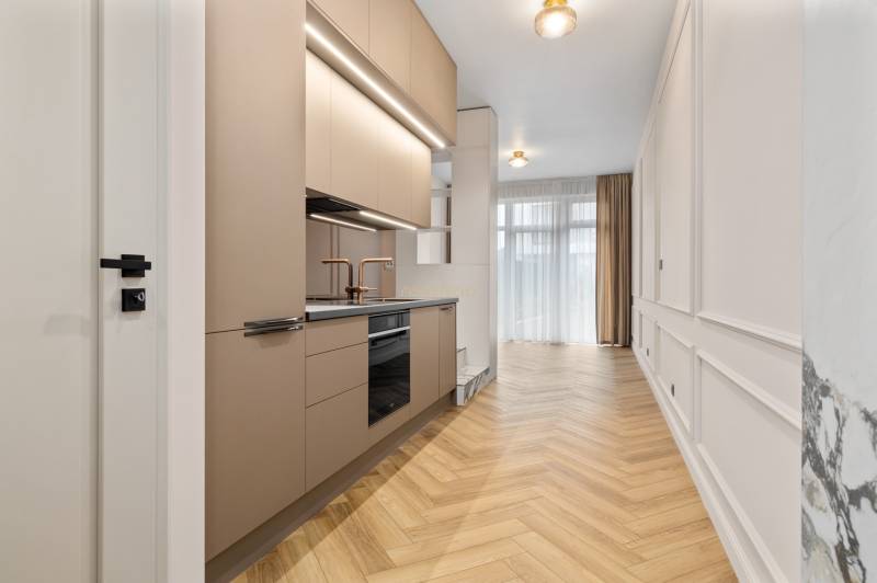 Kuchyně v 2-pokojovém bytě s podlahou s dřevěným dekorem a neutrálními barvami.