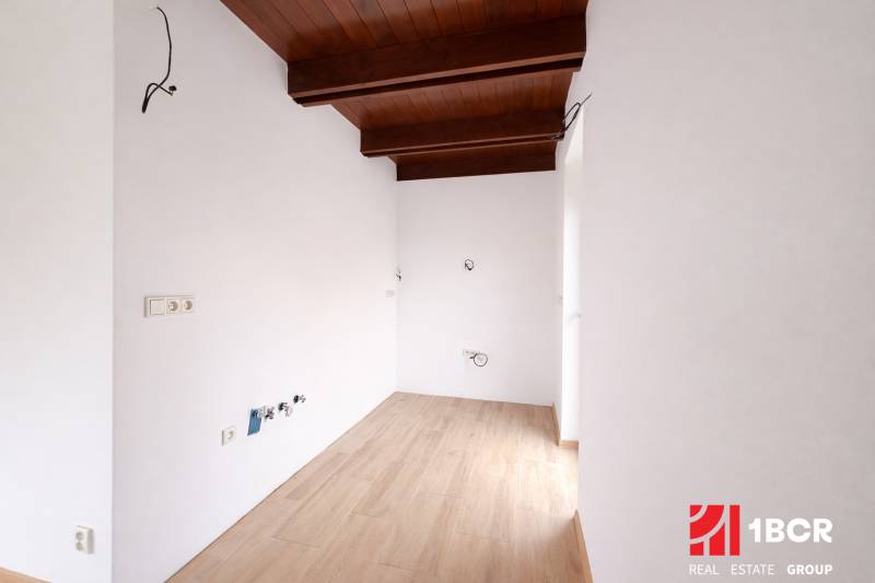 Interiér rodinného domu s podlahou s dřevěným dekorem a dřevěným trámovým stropem.