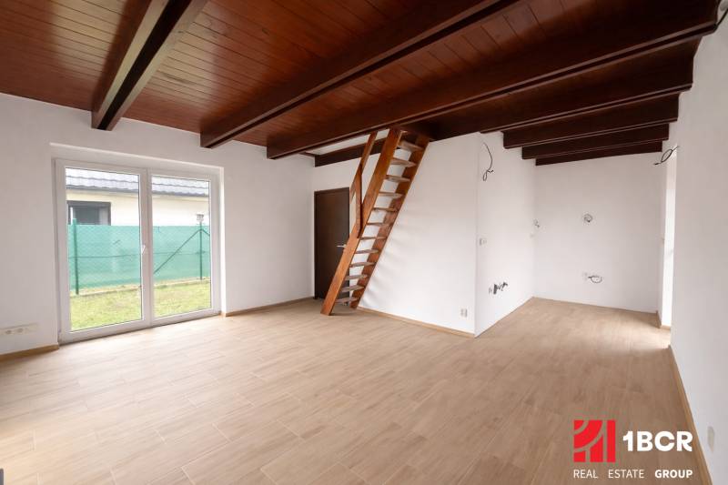 Interiér rodinného domu s žebříkovým schodištěm a podlahou s dřevěným dekorem.