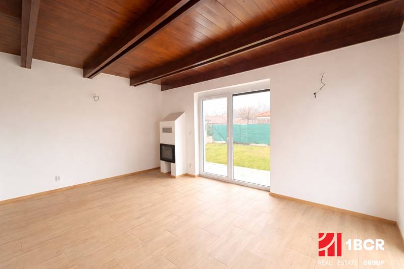 Interiér rodinného domu s podlahou s dřevěným dekorem a s velkými okny do zahrady.