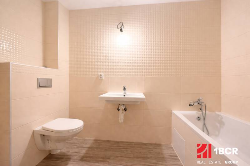 Koupelna v rodinném domě s vanou, umyvadlem a podlahou s dřevěným dekorem.