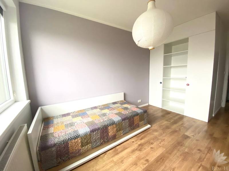 Dětský pokoj v 3pokojovém bytě s postelí a podlahou s dřevěným dekorem.