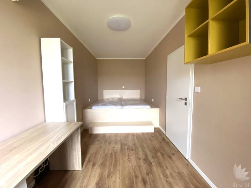 Pokoj ve 3-pokojovém bytě s podlahou s dřevěným dekorem a vestavěným stolem.