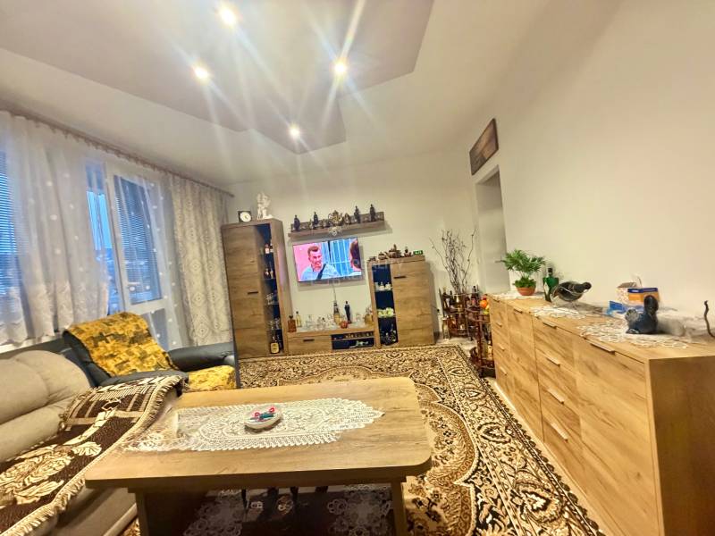 Obývací pokoj v 2-pokojovém bytě s vkusným křeslem, televizorem a kobercem, podlaha s dřevěným dekorem.