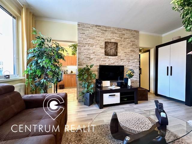 Obývací pokoj v 1-pokojovém bytě s rostlinami a podlahou s dřevěným dekorem.