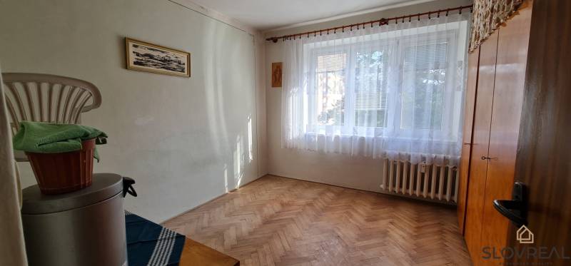 Pokoj s oknem a podlahou s dřevěným dekorem ve 3-pokojovém bytě.