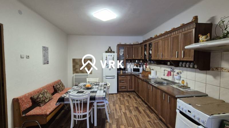 Kuchyně v rodinném domě s dřevěnými skříňkami a podlahou s dřevěným dekorem.