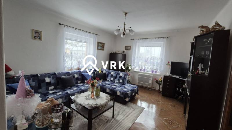 Rodinný dům s pohovkou, skříní, televizorem, dekoracemi a podlahou s dřevěným dekorem.