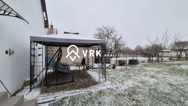 Zasněžená zahrada u rodinného domu na Nové ulici ve Velkých Ozorovcích s altánkem.