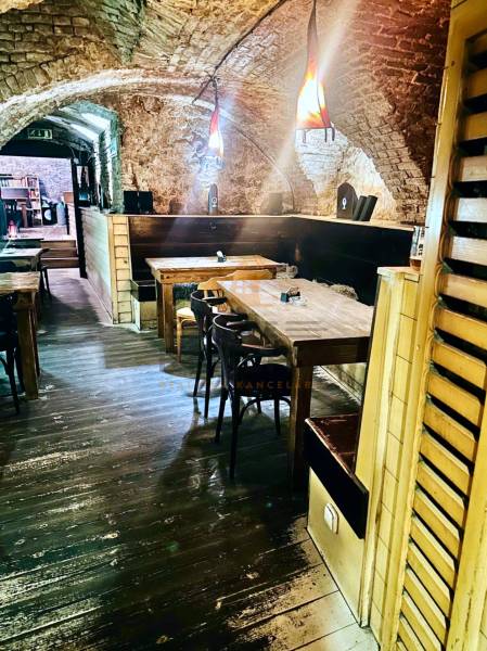 Kamenné stěny a podlaha s dřevěným dekorem vytvářejí útulnou atmosféru v gastro prostorech.