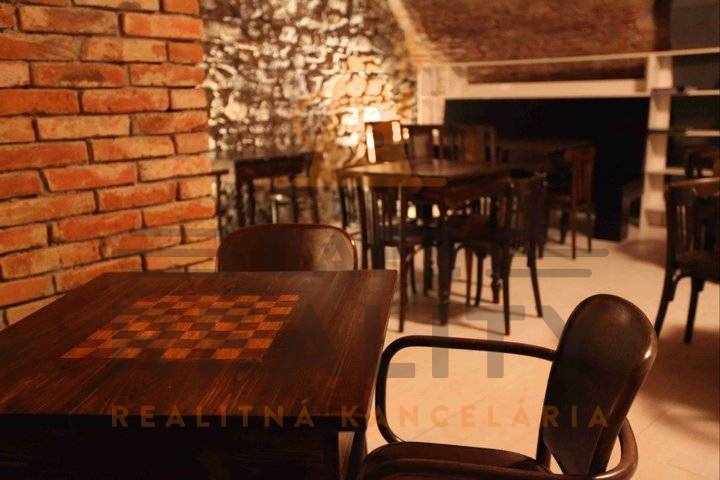 Rustikální gastro prostory s kamennými stěnami a podlahou s dřevěným dekorem.